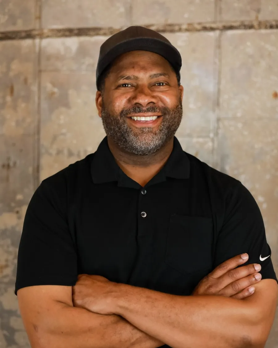Gavin Brooks, founder of Paddock20, smiling in a cap in front of a weathered wall